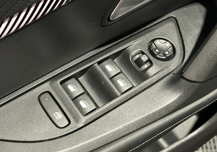 Gros plan sur les commandes de lève-vitres et réglage des rétroviseurs côté conducteur d’un Peugeot 2008 Allure Hybrid 2025.