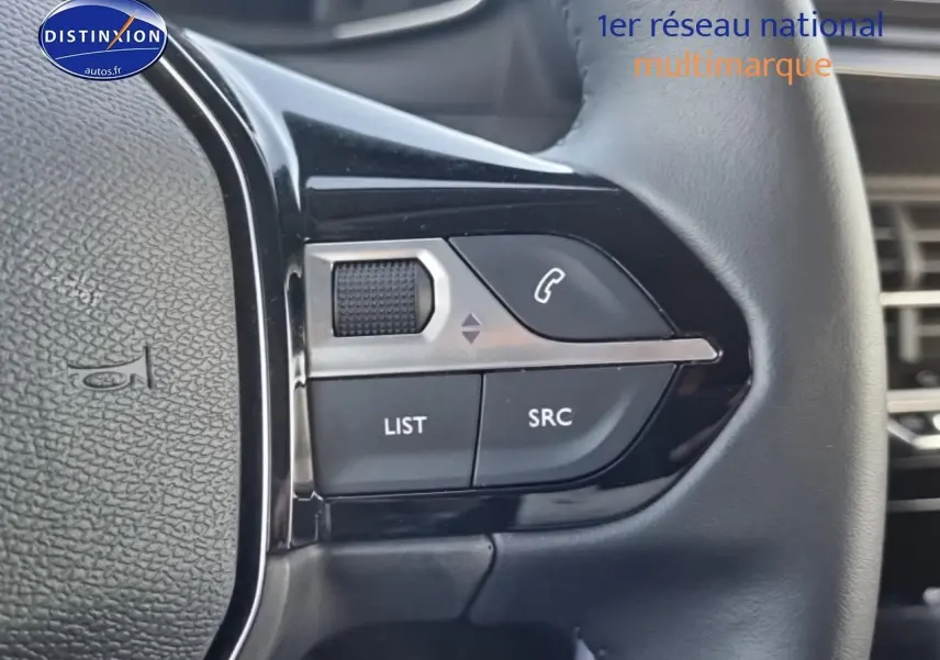 Gros plan sur les commandes audio au volant à gauche d’une Peugeot 208 1.2 PureTech 100 Allure 2024.