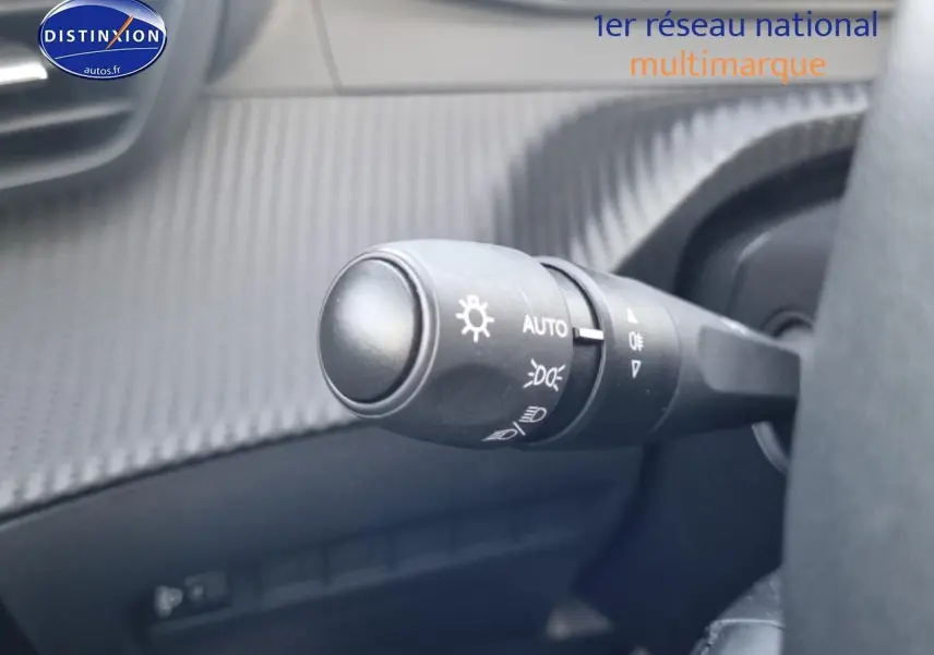 Gros plan sur la commande des phares automatique dans l’habitacle gris d’une Peugeot 208 1.2 PureTech 100 Allure 2024.