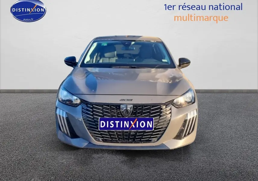 Vue frontale d'une Peugeot 208 1.2 PureTech 100 Allure gris Sélénite avec calandre noire distinctive et phares LED allumés.