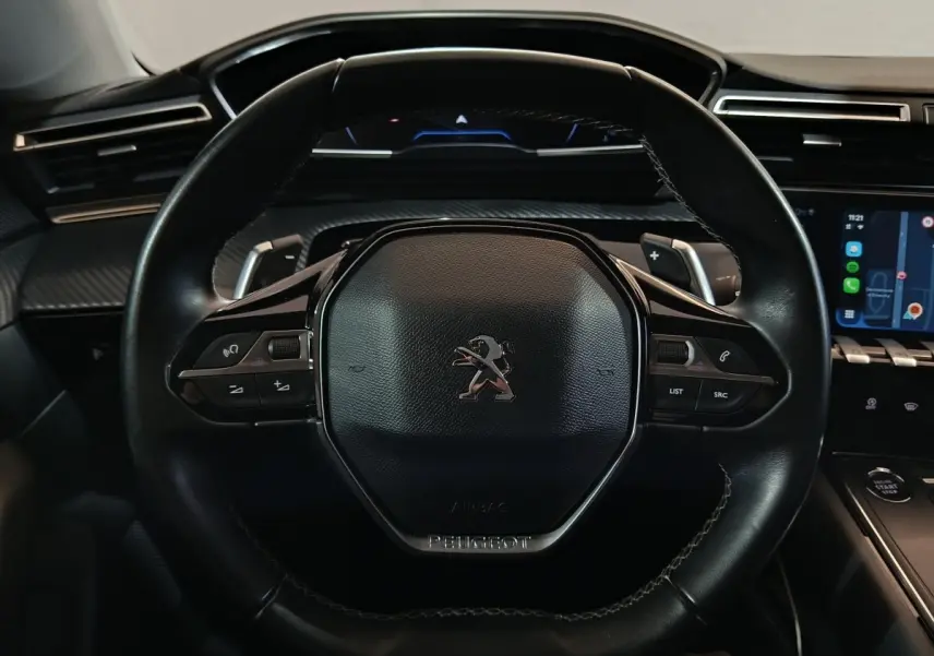 Vue rapprochée du volant cuir noir de la Peugeot 508 2020 avec commandes intégrées et tableau de bord digital.