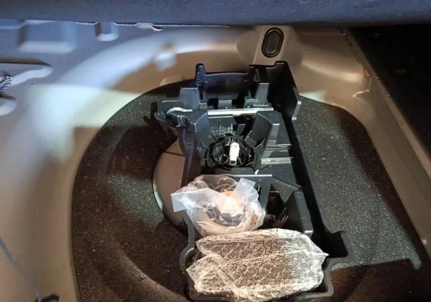 Vue rapprochée du coffre d’une Peugeot 508 gris clair, montrant le rangement pour roue de secours et outils.