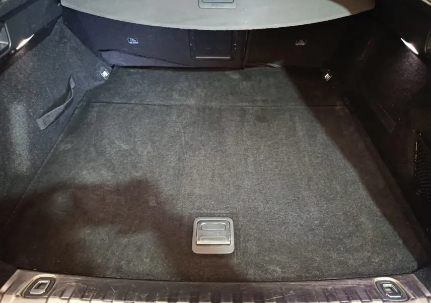 Coffre spacieux de Peugeot 508 gris clair vu de l'arrière, avec tapis noir et éclairage intérieur aux côtés.