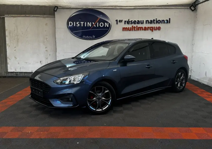 Ford Focus 5 portes bleu en 3/4 avant droit, jantes alliage noires et calandre noire distinctive St-Line.