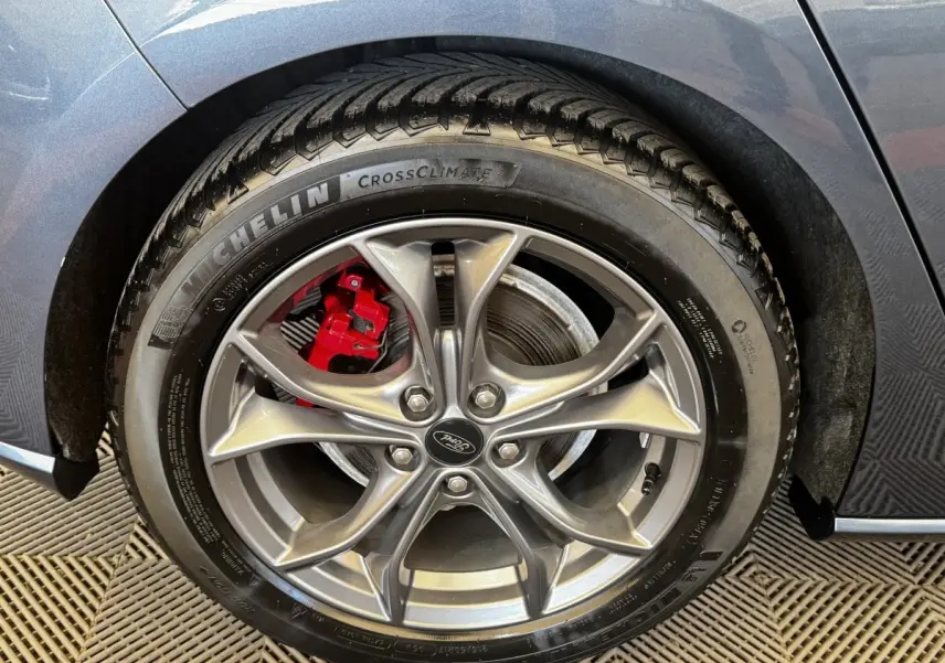 Gros plan sur la roue arrière droite d’une Ford Focus bleu 2022 avec étrier de frein rouge et jante alliage.