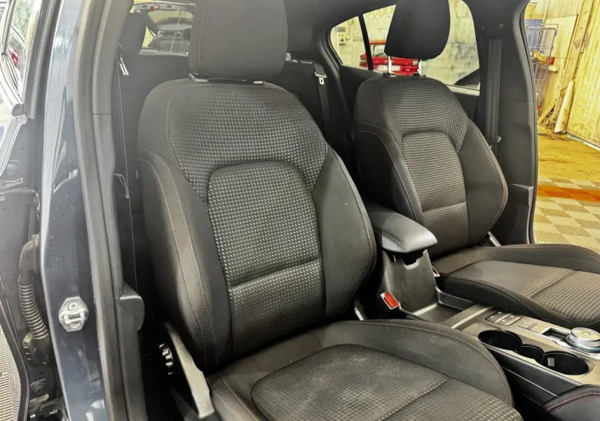 Vue intérieure rapprochée des sièges avant noirs avec surpiqûres rouges d'une Ford Focus 5P bleu 2022.