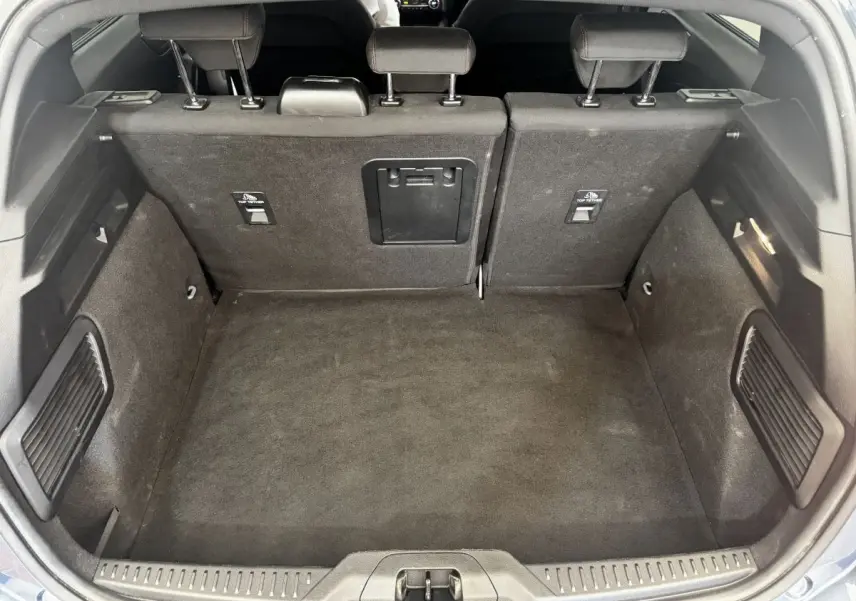 Coffre ouvert vu de l'arrière d'une Ford Focus 5 portes bleu, banquette arrière rabattable 2/3-1/3 visible.