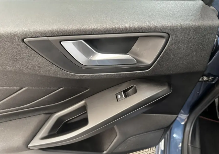 Vue rapprochée de la porte avant gauche bleu foncé de la Ford Focus 5P avec poignée argentée et commande de vitre.