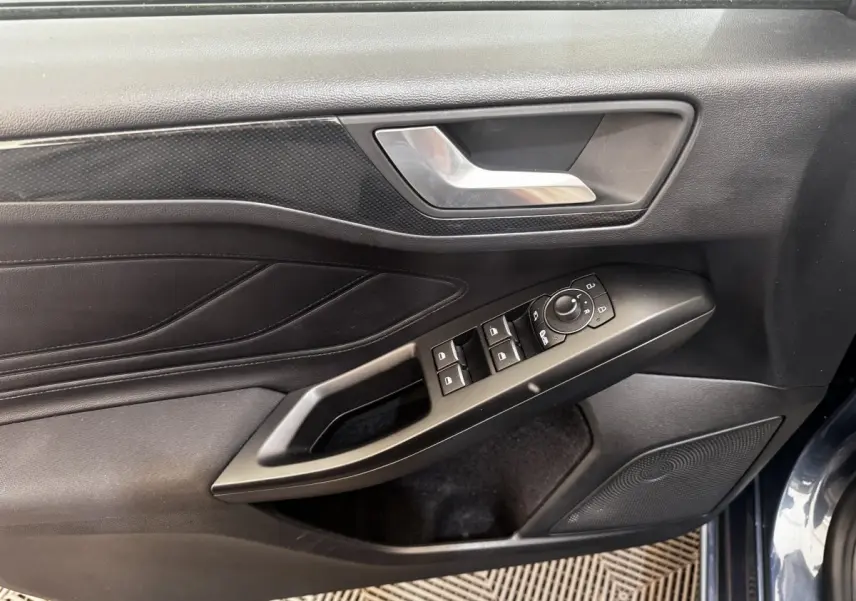 Intérieur porte avant gauche de Ford Focus bleu 2022, avec commandes vitres et rétroviseurs noirs.
