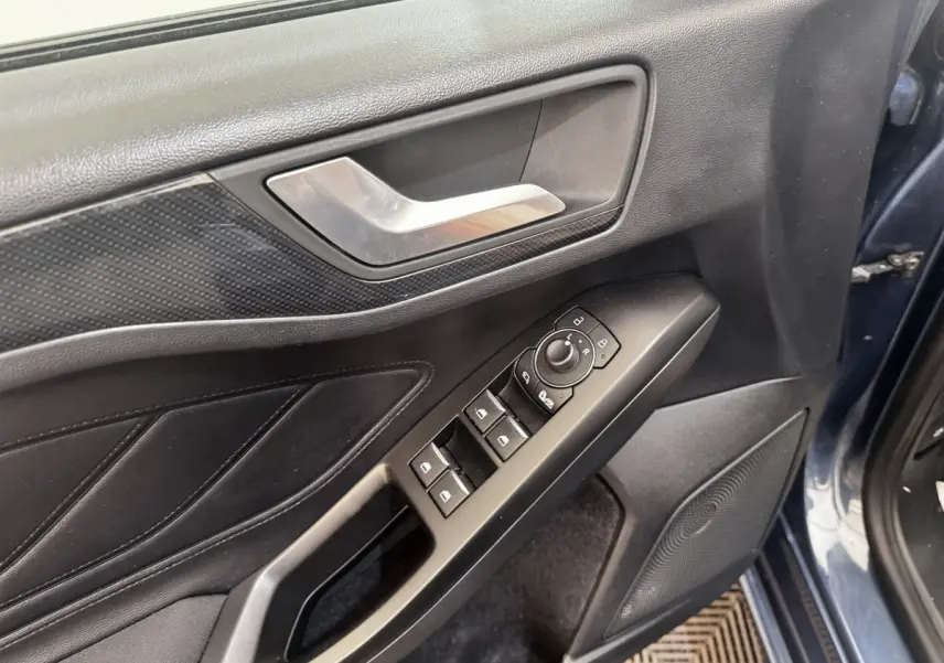 Vue rapprochée de la porte avant gauche bleu foncé de la Ford Focus avec commandes électriques des vitres et rétroviseurs.