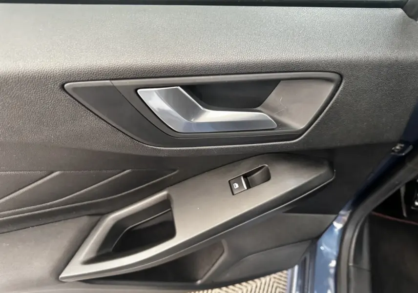 Gros plan sur la poignée intérieure et la commande de vitre côté gauche d’une Ford Focus bleu 5 portes 2022.