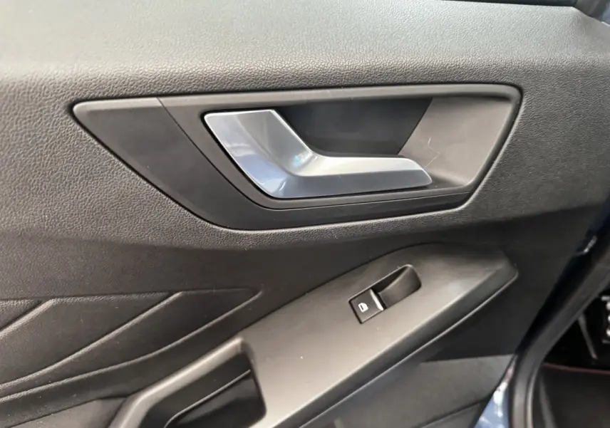 Gros plan sur la poignée intérieure et la commande de vitre côté gauche d'une Ford Focus bleu 5 portes 2022.