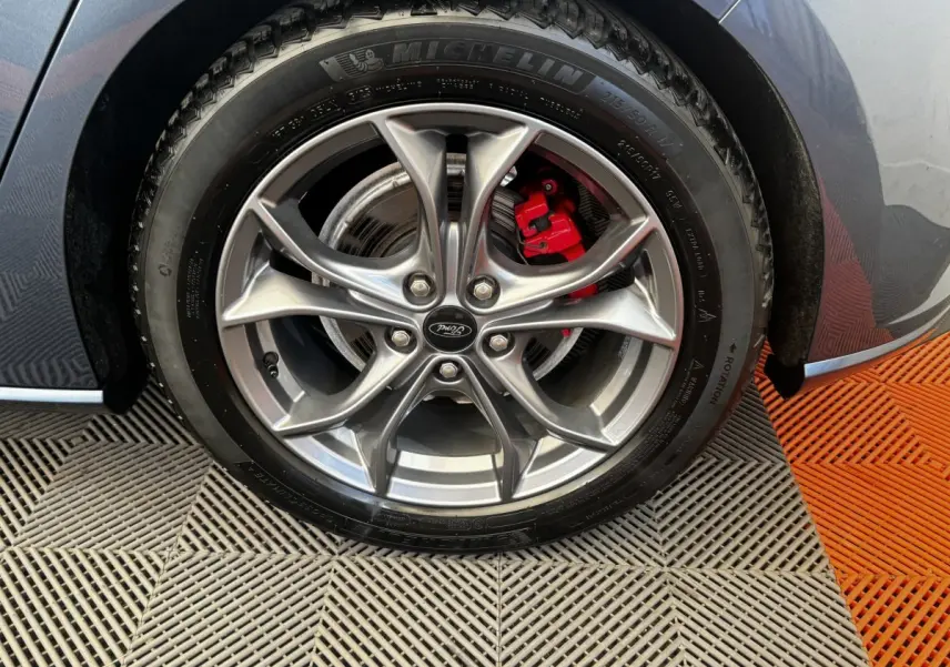 Gros plan sur la roue avant droite d'une Ford Focus bleu 2022, avec jante alliage et étrier de frein rouge visible.