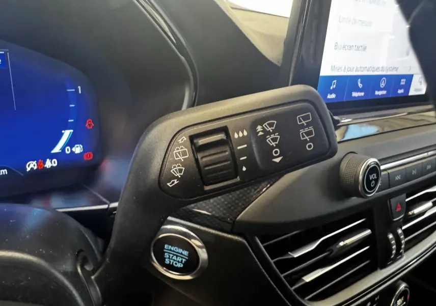 Gros plan sur la commande d'essuie-glace et le bouton start/stop dans l'habitacle de la Ford Focus bleu 2022.