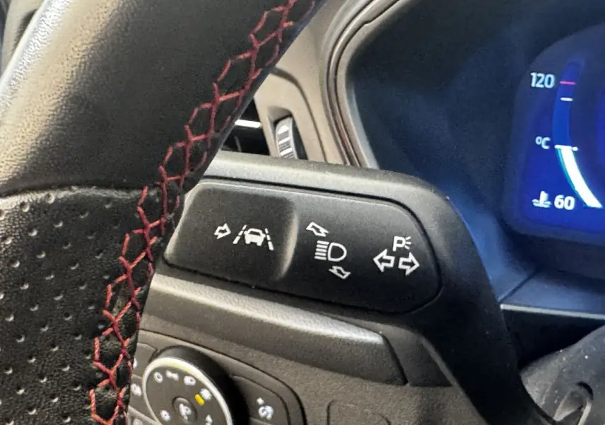 Gros plan sur le volant avec surpiqûres rouges et commandes d’aide à la conduite de la Ford Focus 2022.