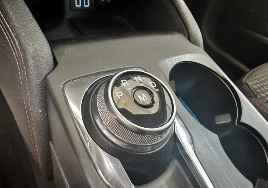 Gros plan sur la molette de boîte automatique noire et chrome au centre de la console d'une Ford Focus bleu St-Line.