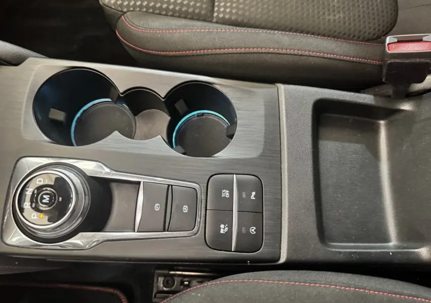 Vue plongeante sur la console centrale noire de la Ford Focus St-Line 2022 avec molette de boîte auto et porte-gobelets.