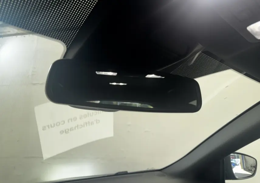 Vue intérieure centrée sur le rétroviseur intérieur d'une Ford Focus bleue, avec partie du pare-brise et rétroviseur latéral droit visible.
