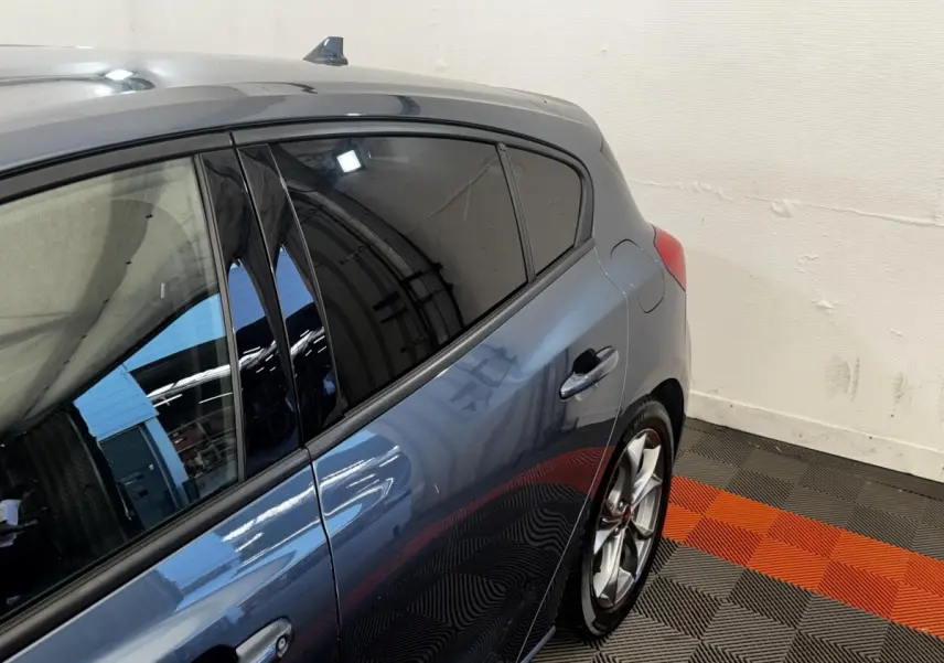 Vue côté droit arrière d'une Ford Focus 5 portes bleu métallisé avec vitres teintées et jantes alliage sport.