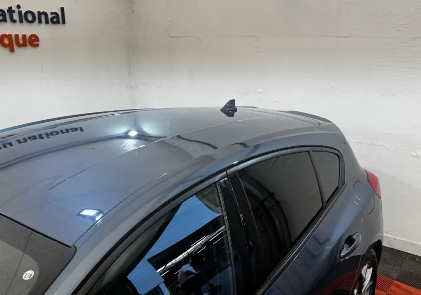 Vue 3/4 arrière droite d'une Ford Focus 5 portes bleu métallisé avec vitres teintées en intérieur showroom.