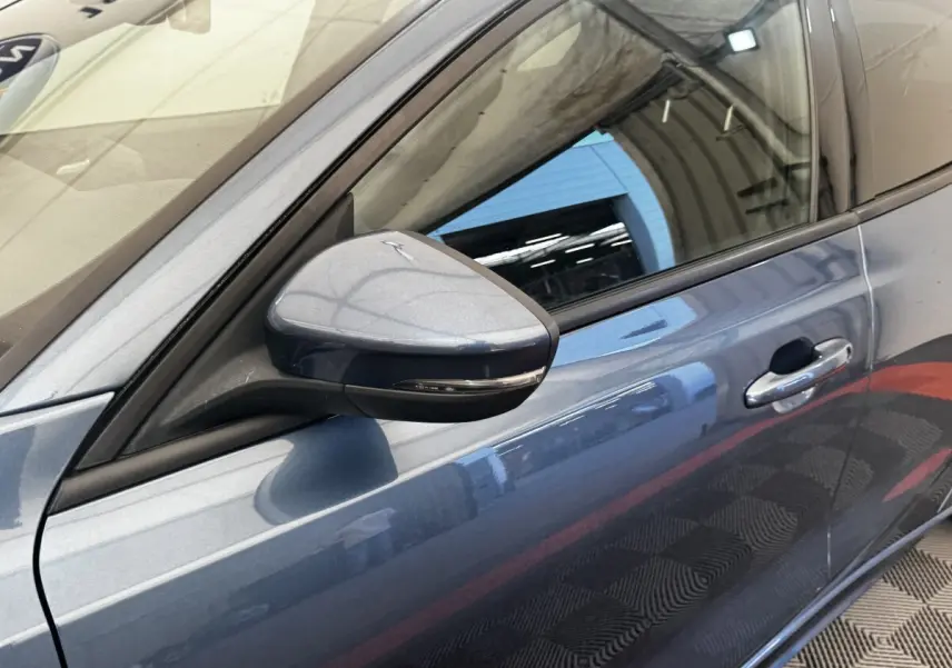 Gros plan sur le rétroviseur côté gauche et la porte avant bleu métallisé d’une Ford Focus 5P St-Line 2022.