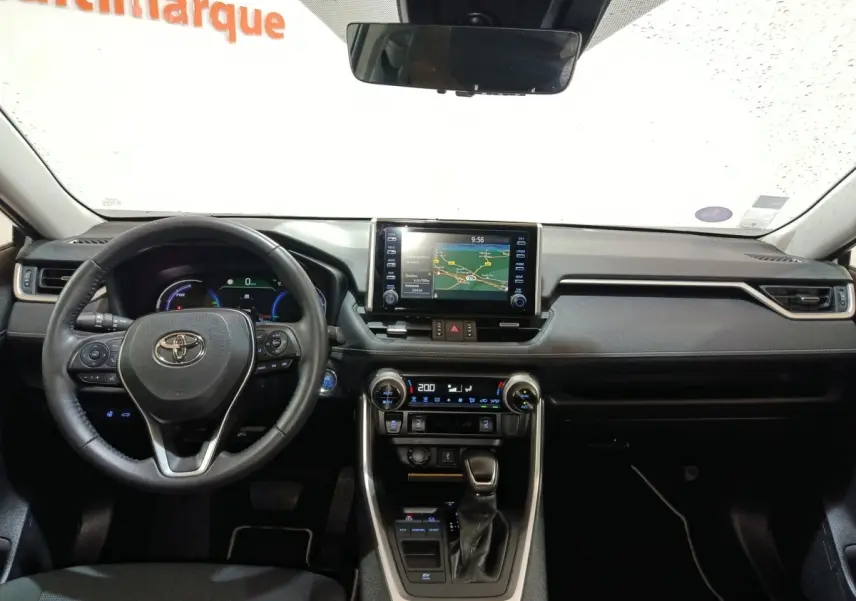 Vue intérieure frontale du tableau de bord noir du Toyota RAV4 hybride avec écran tactile central et volant cuir multifonctions.