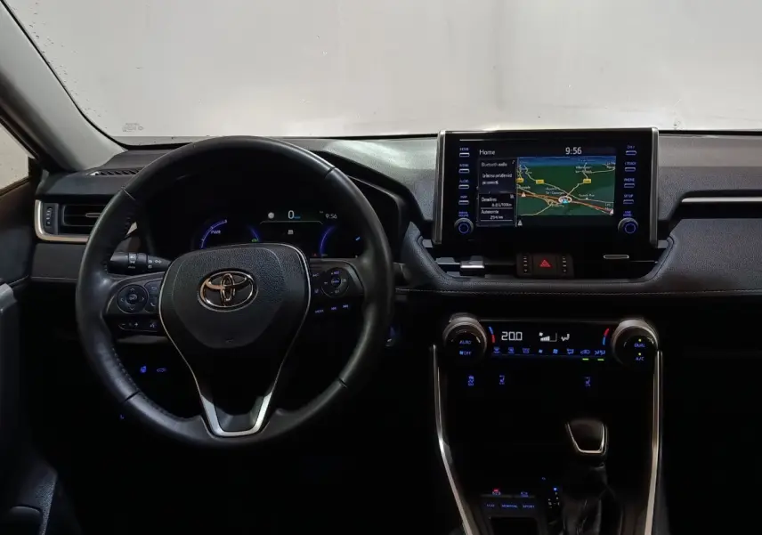 Vue intérieure du tableau de bord du Toyota RAV4 Hybride 2021, avec volant cuir et écran tactile central allumé.
