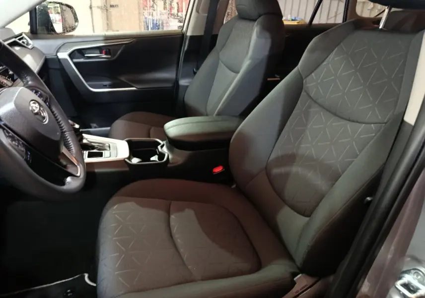 Vue intérieure côté conducteur du Toyota RAV4 Hybride 2WD 218ch Dynamic 2021 avec sièges tissu gris et console centrale noire.
