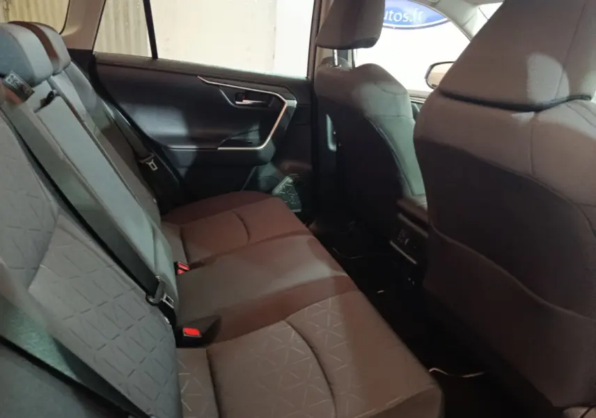 Vue intérieure montrant la banquette arrière grise du Toyota RAV4 hybride 2021, avec ceintures de sécurité et portes latérales.