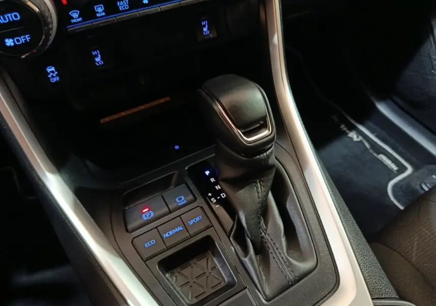 Gros plan sur la console centrale du Toyota RAV4 hybride 2021, montrant levier de vitesses et boutons modes de conduite.