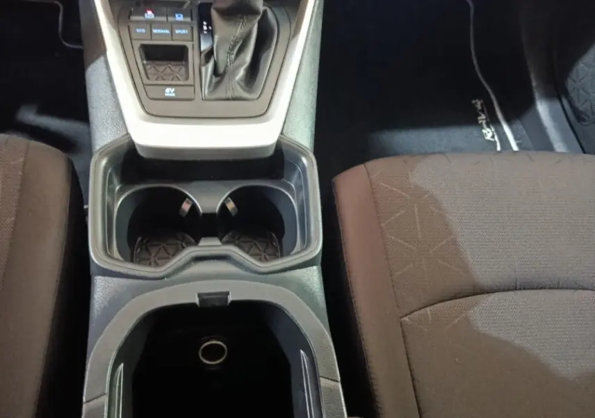Vue intérieure centrée sur la console centrale noire avec levier de vitesse et sièges tissu marron foncé du Toyota RAV4.