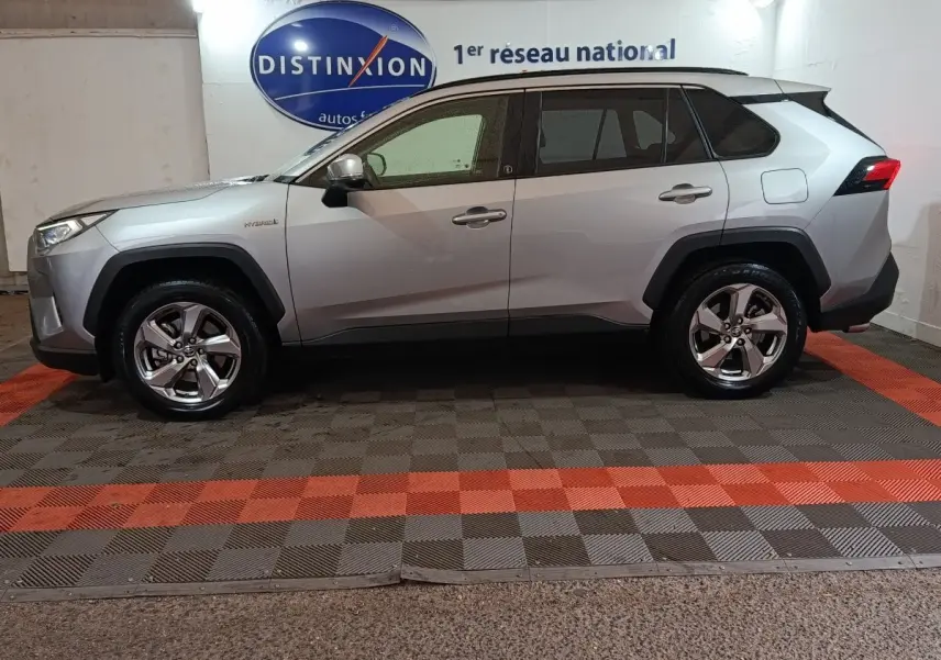 Profil droit d'un Toyota RAV4 hybride 2WD gris clair, avec jantes alliage et détails noirs autour des passages de roues.
