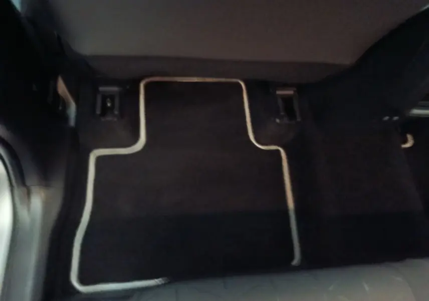 Plancher arrière avec tapis noir bordé de beige dans un Toyota RAV4 Hybride 2WD 218ch, vue centrée au sol.