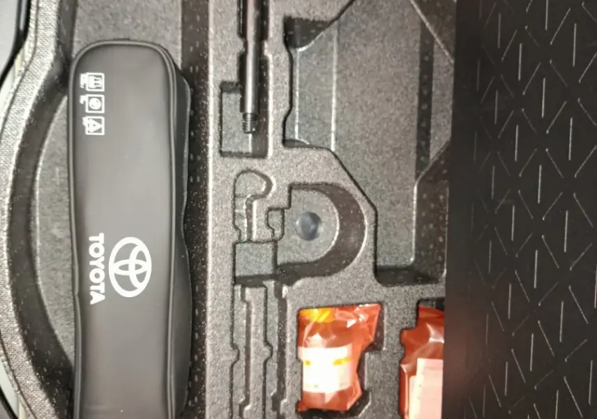 Vue rapprochée de la trousse à outils et accessoires dans le coffre du Toyota RAV4 hybride 2021, rangement en mousse noire.