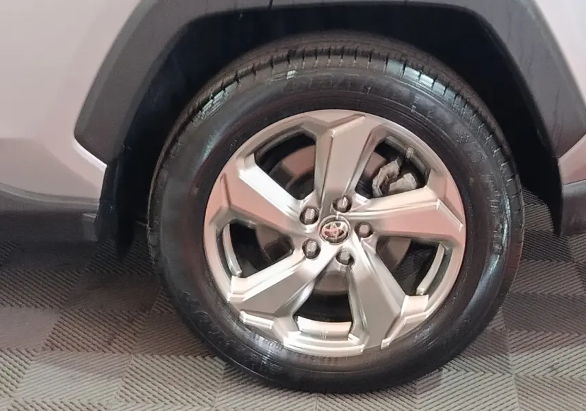 Gros plan sur la roue avant droite du Toyota RAV4 hybride 2021 avec jante alliage argentée et carrosserie claire.