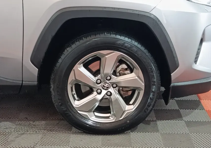 Gros plan sur la roue avant droite argentée du Toyota RAV4 Hybride 2021 avec carrosserie blanche visible.