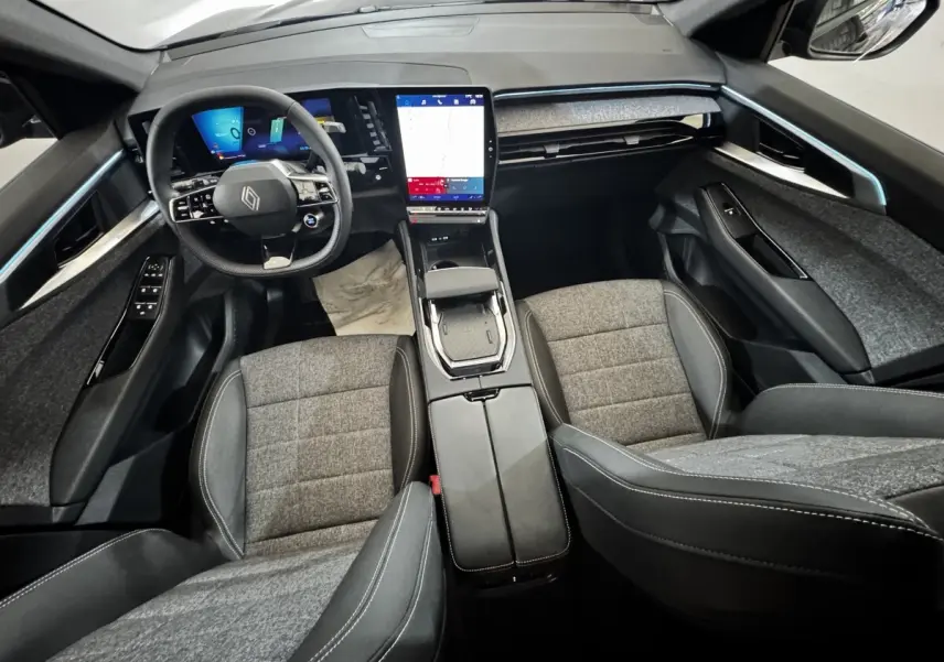 Vue intérieure avant du Renault Espace 2025 noir, tableau de bord moderne avec grand écran tactile vertical et volant multifonctions.