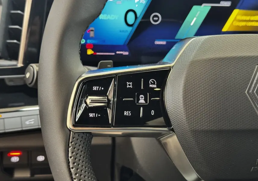 Gros plan sur la partie gauche du volant noir du Renault Espace 2025 avec commandes de régulateur et écran numérique en arrière-plan.