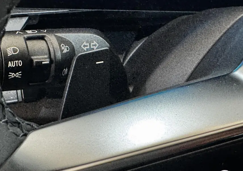 Gros plan sur la commande des feux et clignotants à gauche du volant d'un Renault Espace noir 2025.