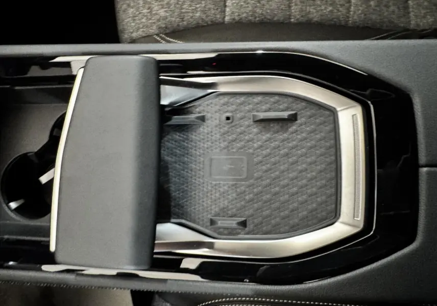 Vue plongeante sur la console centrale noire du Renault Espace 2025 avec zone de recharge sans fil et accoudoir rembourré.