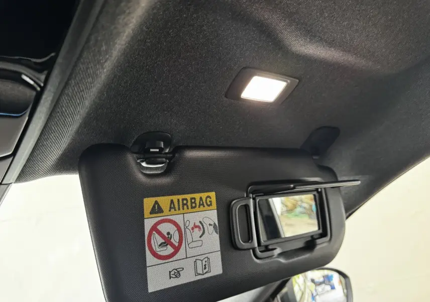 Détail intérieur du pare-soleil côté conducteur avec miroir et avertissement airbag, éclairage intérieur allumé, Renault Espace noir.