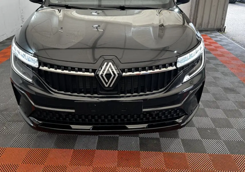 Vue frontale rapprochée du Renault Espace noir 2025 avec calandre chromée et phares LED allumés.