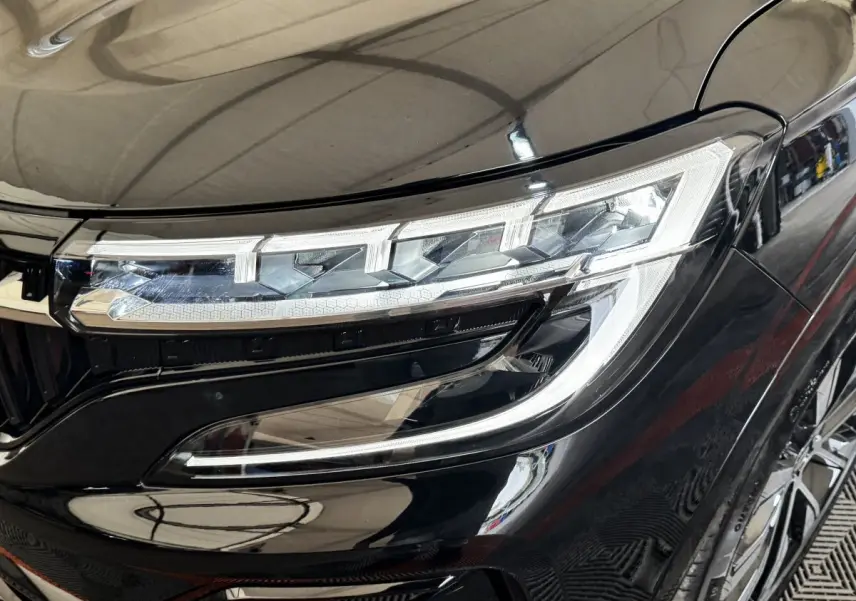 Gros plan sur le phare avant droit du Renault Espace noir 2025 avec détails LED et carrosserie brillante.