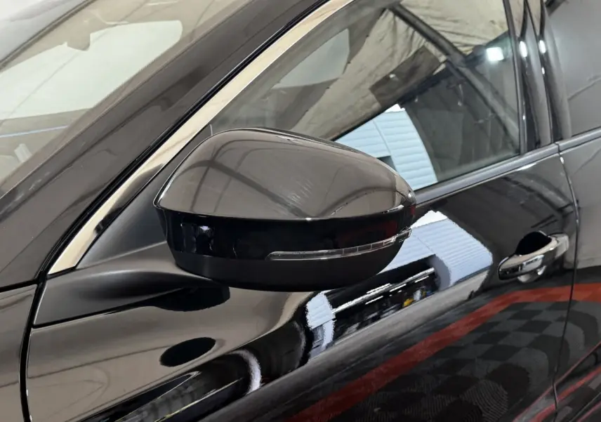 Gros plan sur le rétroviseur côté gauche noir brillant du Renault Espace 2025 avec poignée de porte et partie de la vitre.
