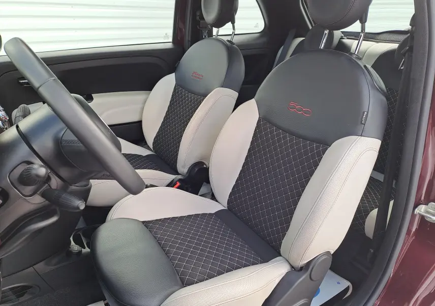 Vue intérieure côté conducteur de la FIAT 500 2020 Opera Bordeaux, sièges bi-matière noirs et beige avec logo 500 brodé rouge.