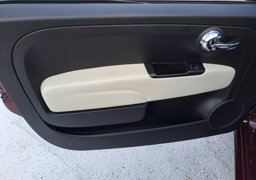 Gros plan sur la porte côté gauche de la FIAT 500 Opera Bordeaux Metal, avec garniture beige et poignée chromée.