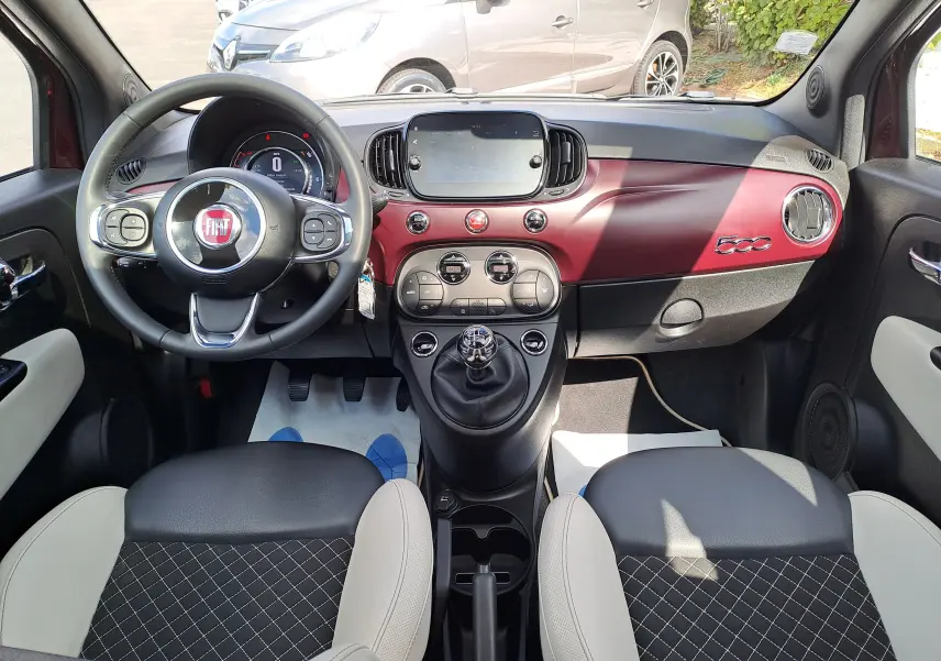 Vue intérieure frontale du tableau de bord bordeaux Opera avec volant Fiat et sièges noirs et blancs du Fiat 500 2020.