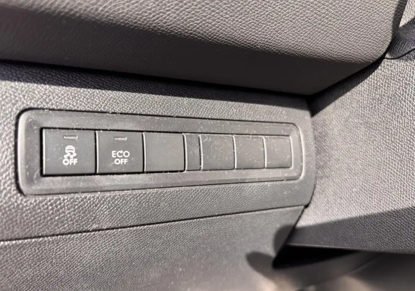 Boutons de commande de désactivation de l'ESP et mode ECO sur la planche de bord d'une Peugeot 308 rouge foncé GT Line.