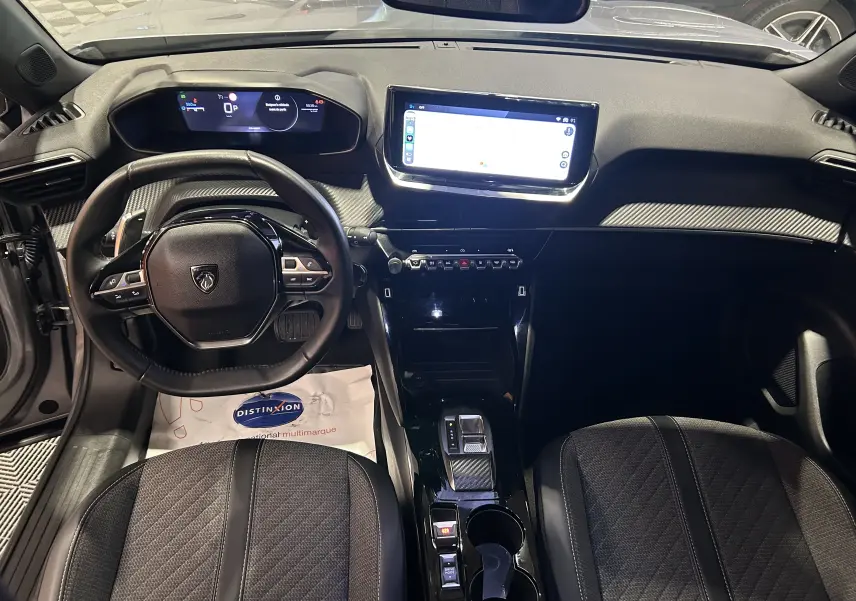 Intérieur du Peugeot 2008 Allure Hybrid 145, vue du poste de conduite avec écran tactile et volant compact noir.