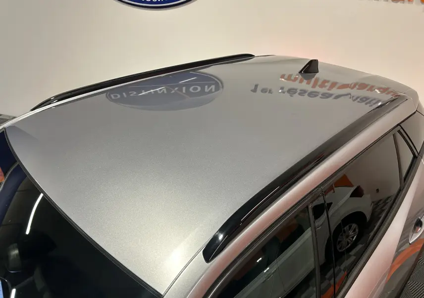 Toit gris métallisé du Peugeot 2008 Allure Hybrid 145 vu en plongée, avec barres de toit noires et vitres teintées.